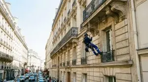 Cordiste professionnel intervenant sur la façade d'un immeuble haussmannien, une alternative à l'entreprise de travaux en hauteur Paris.